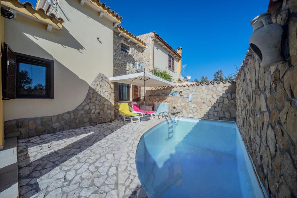 a house with a swimming pool next to a stone wall at Villa Tiziana&Alessia in Castiadas