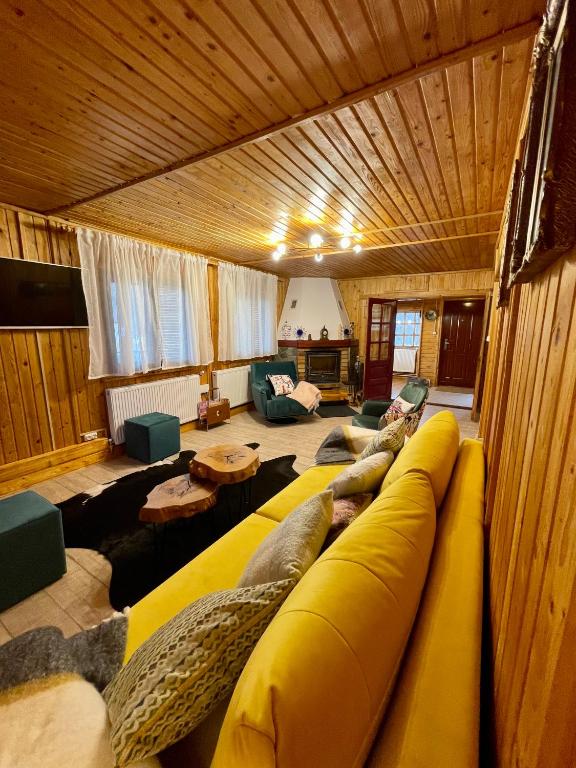 a large yellow couch in a living room at Cabana din Poveste Valea Doftanei in Trăisteni