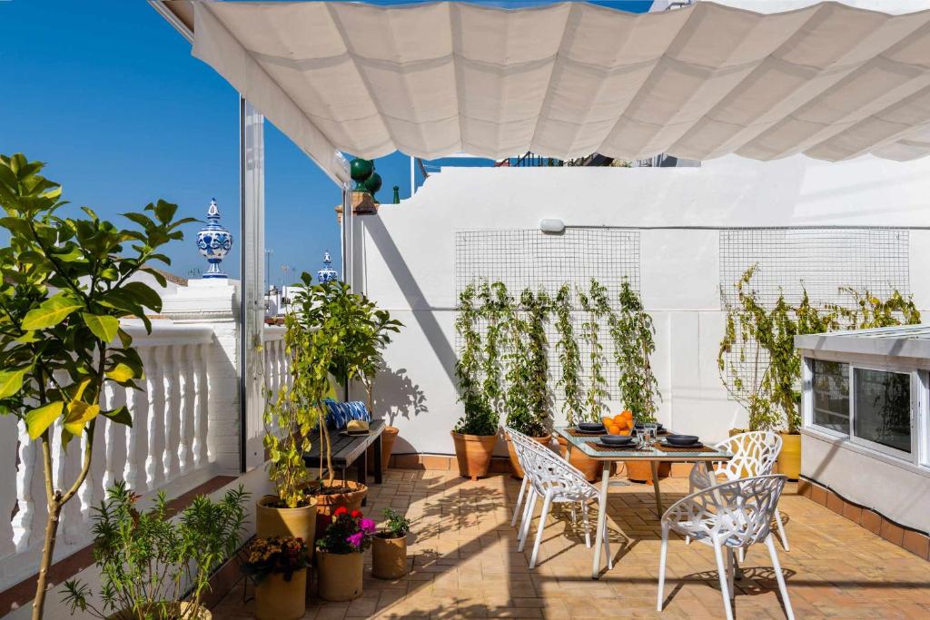 eine Terrasse mit einem Tisch, Stühlen und Topfpflanzen in der Unterkunft MonKeys Apartments Luxury Penthouse Pureza & Chill Out in Sevilla