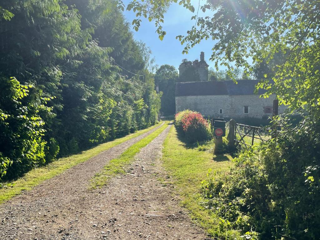 a dirt road leading to a house with a building at Grange à grains à l'Ombre d'une Tour in Tournebu