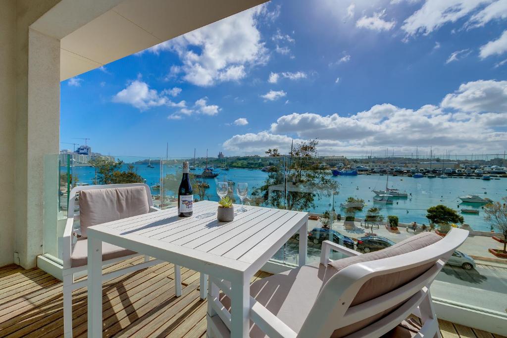 een witte tafel en stoelen op een balkon met uitzicht op het water bij Luxury Apartment with Valletta and Harbour Views in Sliema