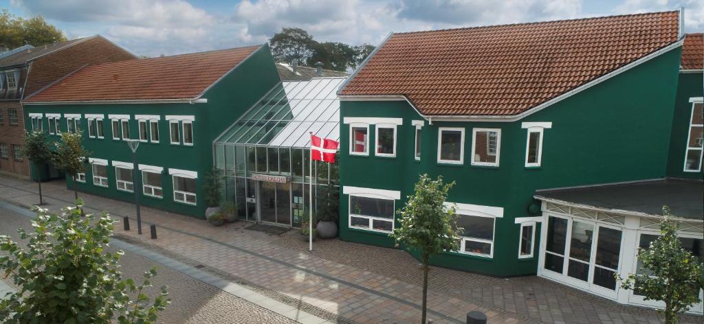 a group of green buildings on a street at Hotel Dalgas in Brande