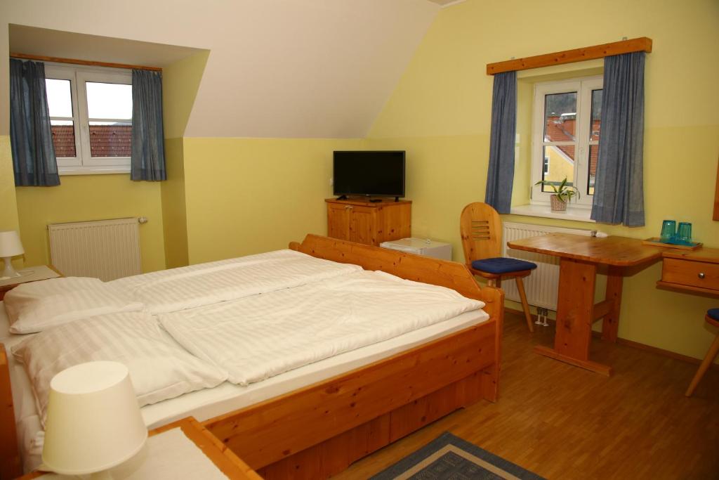 a bedroom with a bed and a desk and a television at Pernegger Dorfstub´n in Pernegg an der Mur
