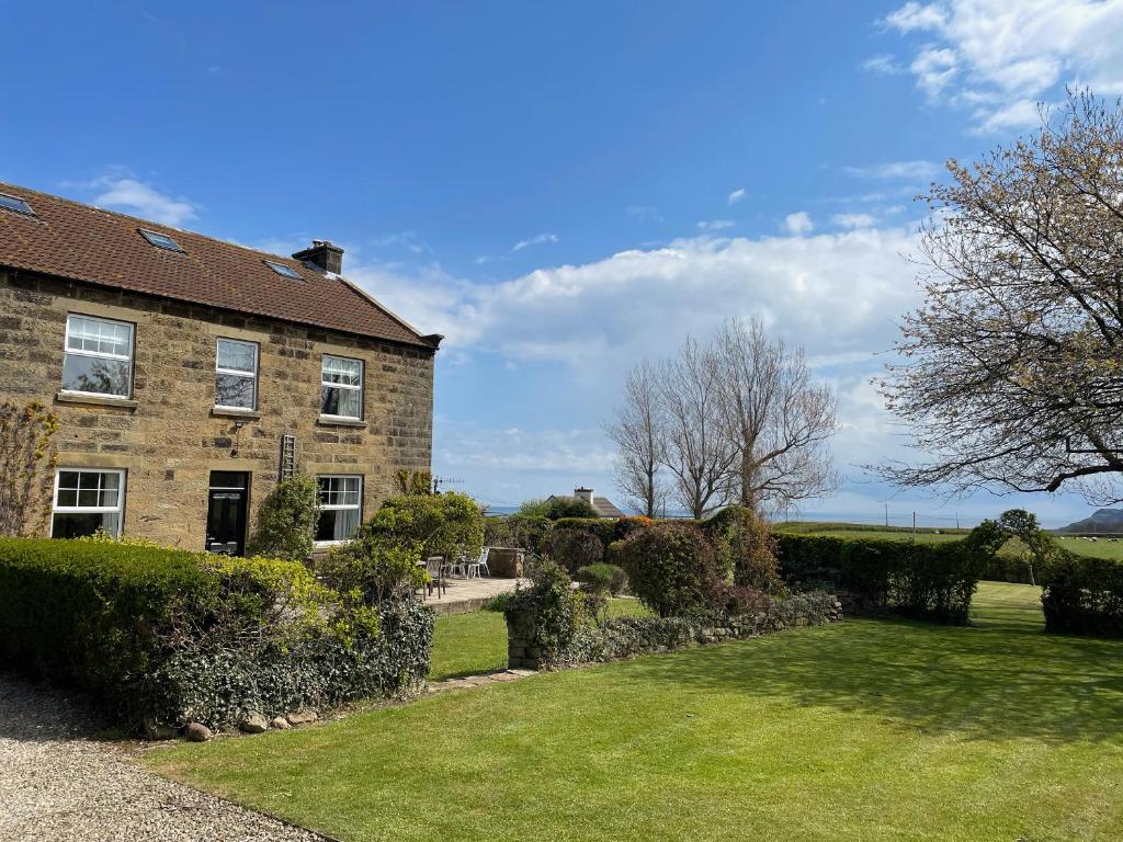 a large brick house with a garden in front of it at The Farmhouse in Whitby