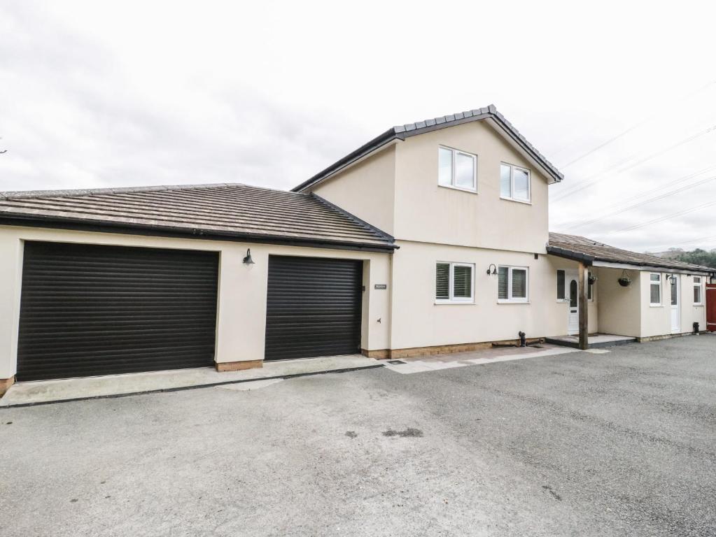 a house with two garage doors in a parking lot at Bryn Derw Holiday Cottage in Eglwys-Fâch