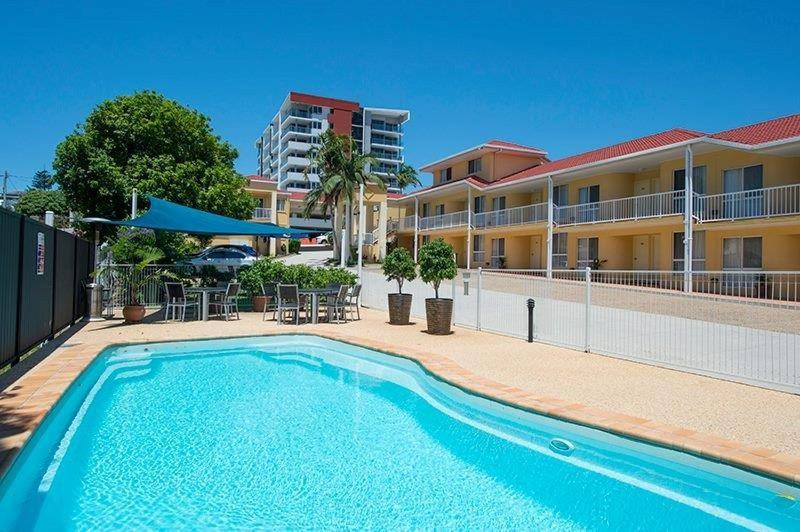 a swimming pool in front of a building at Harbour Sails Motor Inn in Gladstone