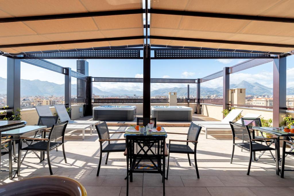 een patio met tafels en stoelen en uitzicht op de stad bij Palermo Blu - Multi Suite in Palermo