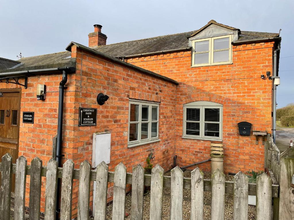 a brick house with a fence in front of it at Stables Cottage in East Norton