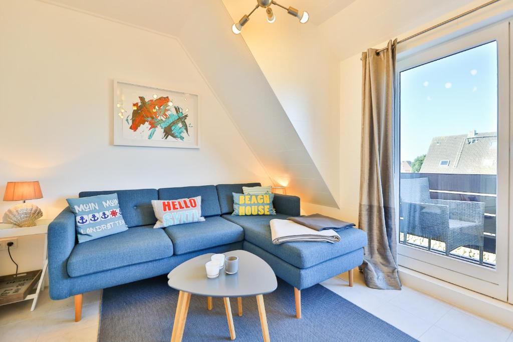 uma sala de estar com um sofá azul e uma janela em Appartement Auszeit em Wenningstedt