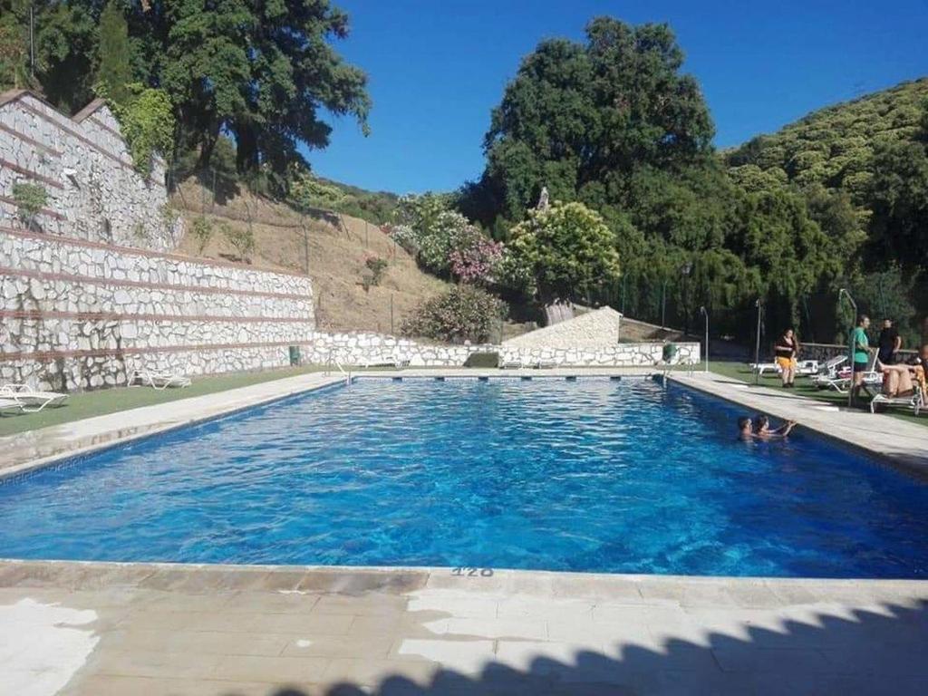 a large swimming pool with blue water in front of a mountain at Casas Rurales El Viejo Castaño 1 in Pujerra