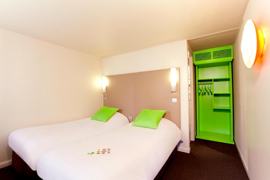 ランスにあるカンパニーユ ランスの緑色のアクセントが施された部屋のベッド2台