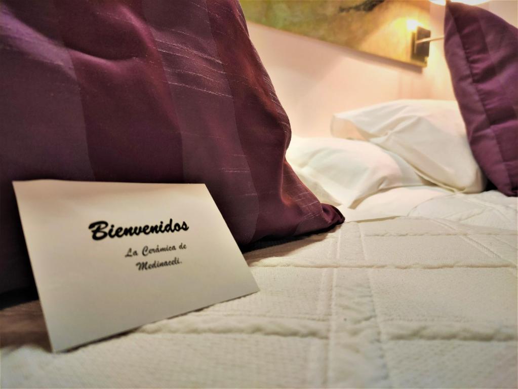 Hotel Rural La Cerámica في مديناسيلي: وجود علامة للجلوس فوق السرير