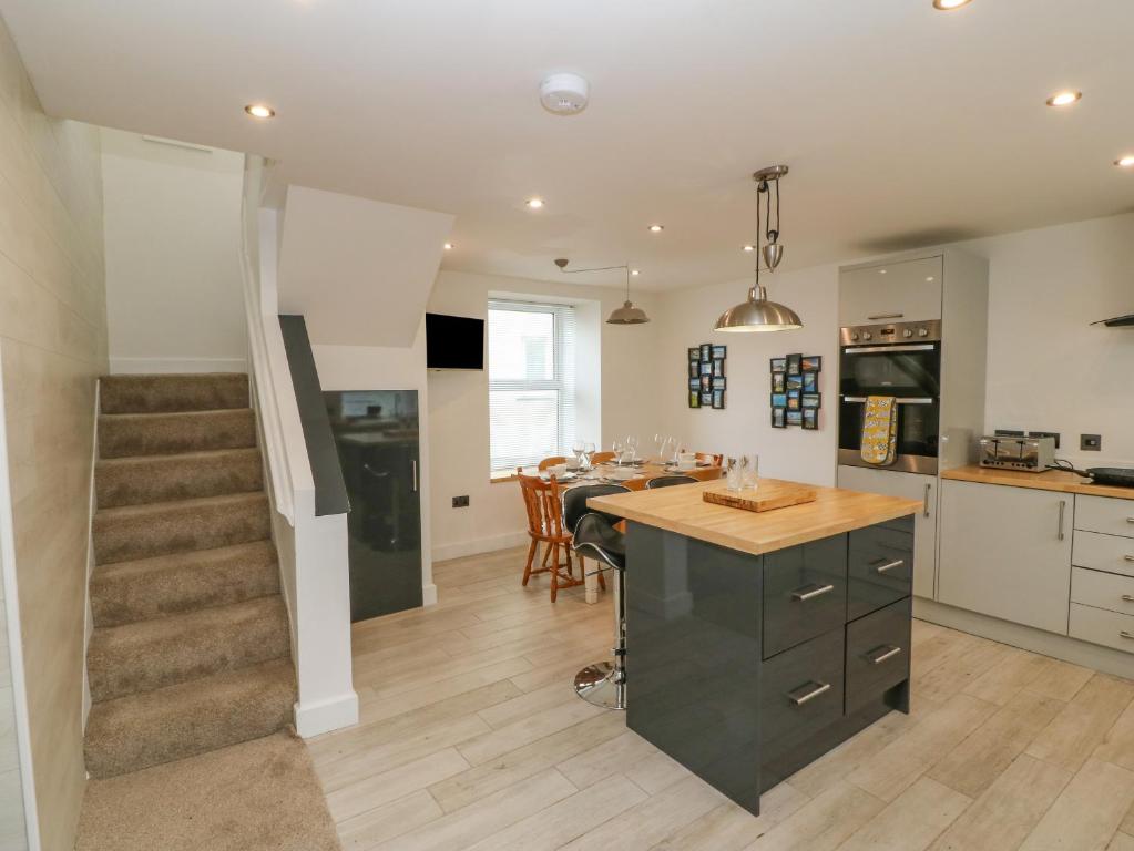 a kitchen and dining room with a table and a staircase at Bryngolau in Pwllheli