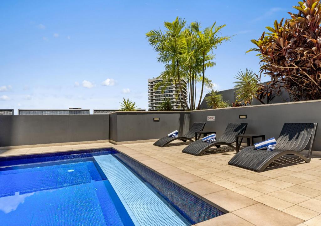 a swimming pool with two lounge chairs next to at H on Mitchell Apartment Hotel in Darwin