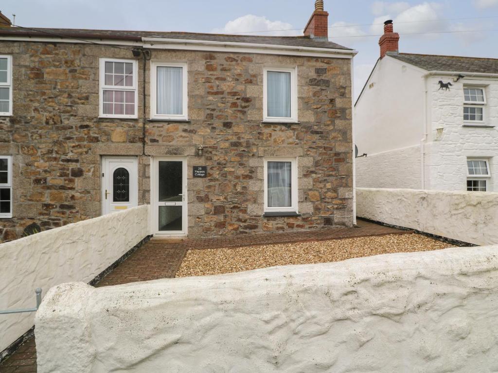 a brick house with a stone wall in front of it at Nappers Cottage in Hayle