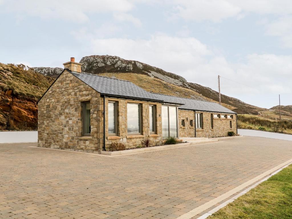 a stone house with a hill in the background at House Crohy Head in Dungloe