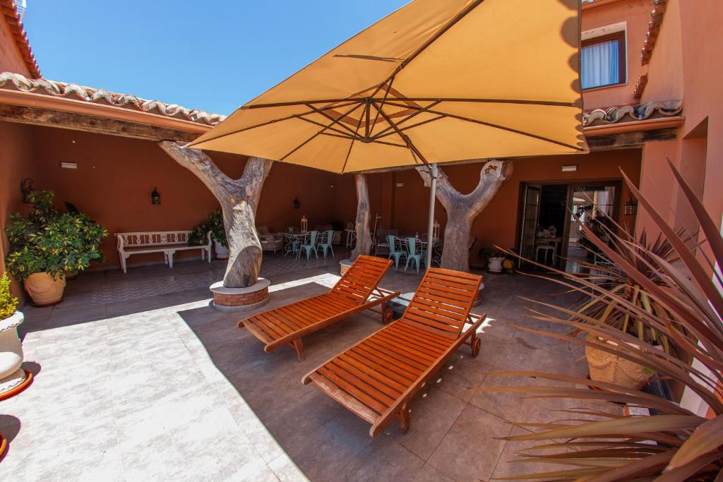 - une terrasse avec 2 chaises et un grand parasol dans l'établissement Casa Rural La Pajarona, à Siruela