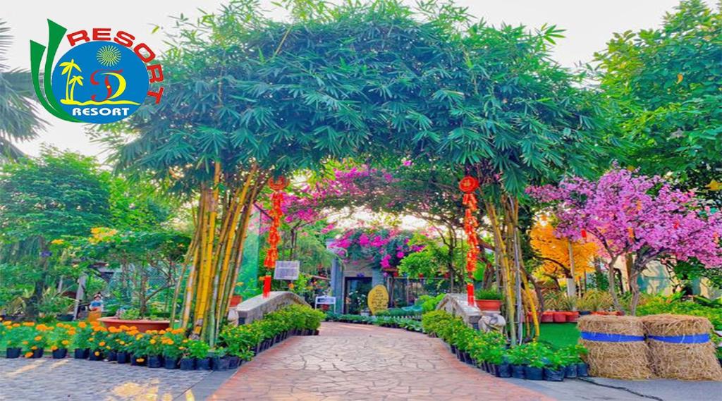 a garden with trees and flowers and a walkway at Thanh Dat Resort in Can Tho