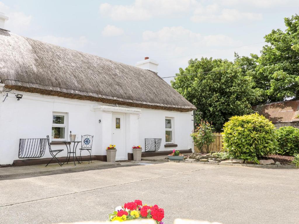 a white cottage with a thatched roof and flowers at Whispering Willows - The Thatch in Craigtown