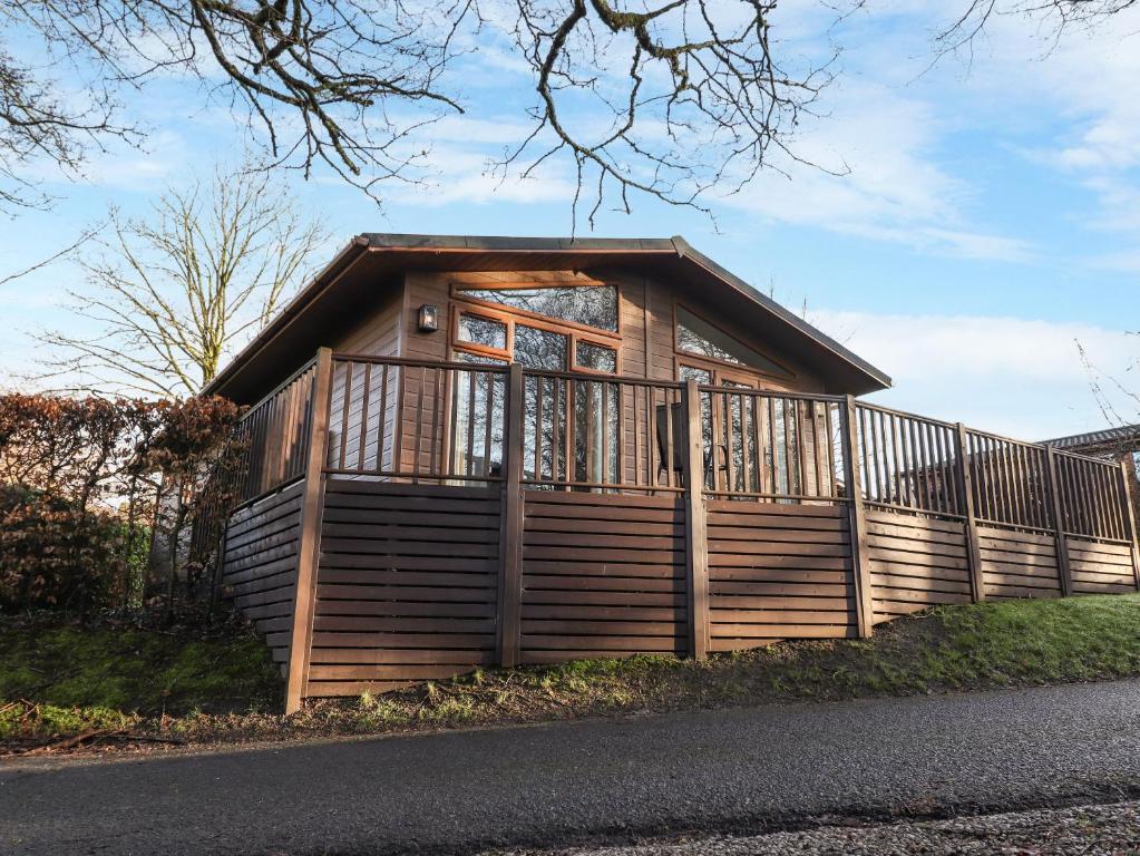 ein kleines Holzhaus mit einem Zaun drum herum in der Unterkunft Westbrook Lodge in Bowness-on-Windermere