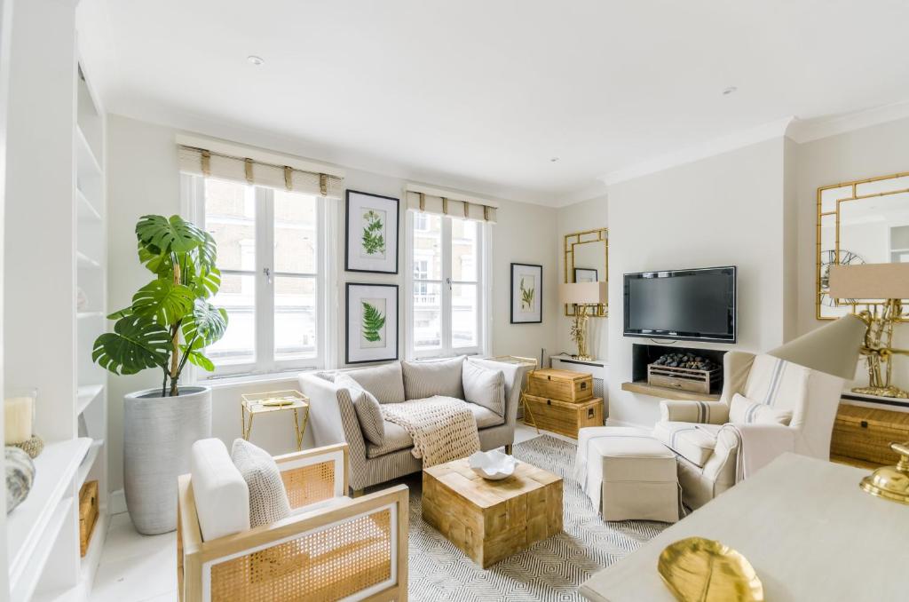 a living room with white furniture and a flat screen tv at ALTIDO Elegant 2-bed, 2 bath flat with private terrace in South Kensington, close to tube in London