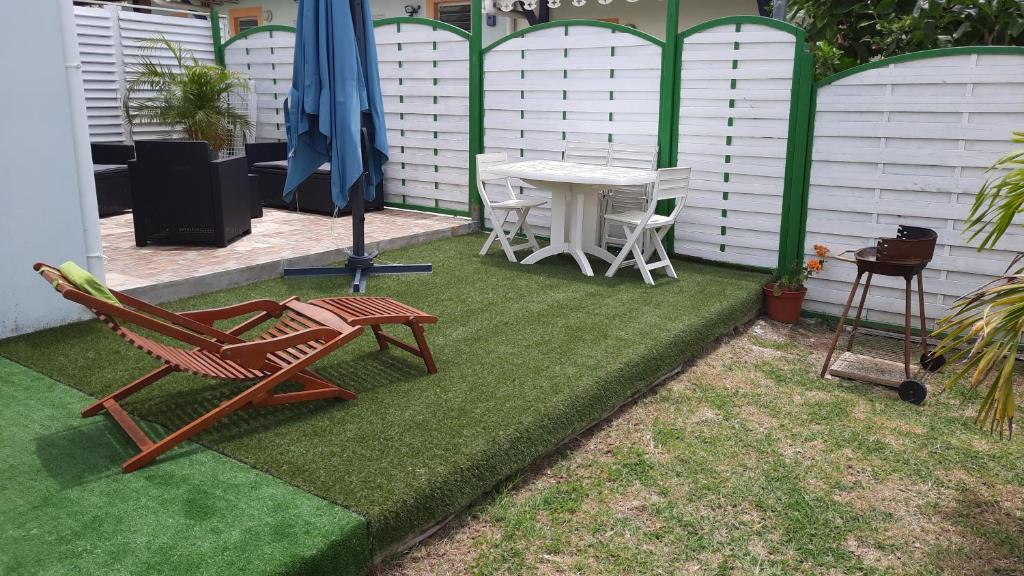 a patio with a table and chairs on the grass at Gîte Muskad in Sainte-Anne