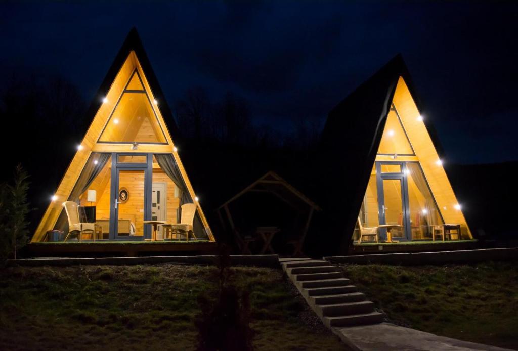 una casa con techo triangular por la noche en Casute din lemn, en Jiblea Veche