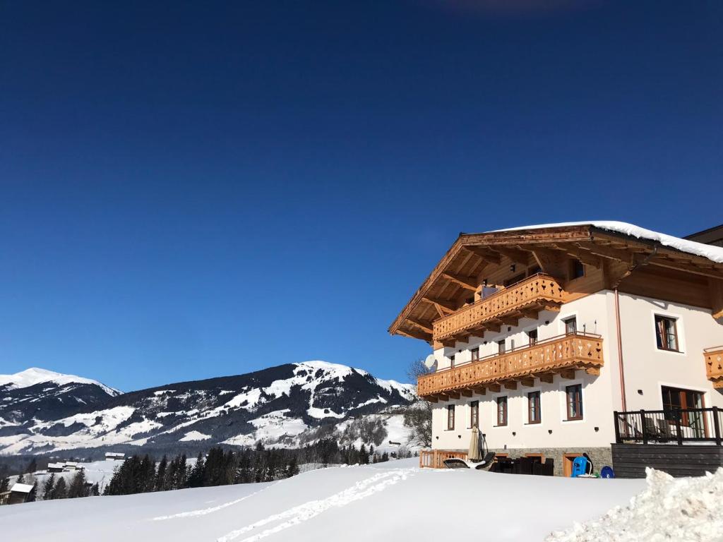 a building in the snow with mountains in the background at Ferienwohnungen Unterhof in Mittersill
