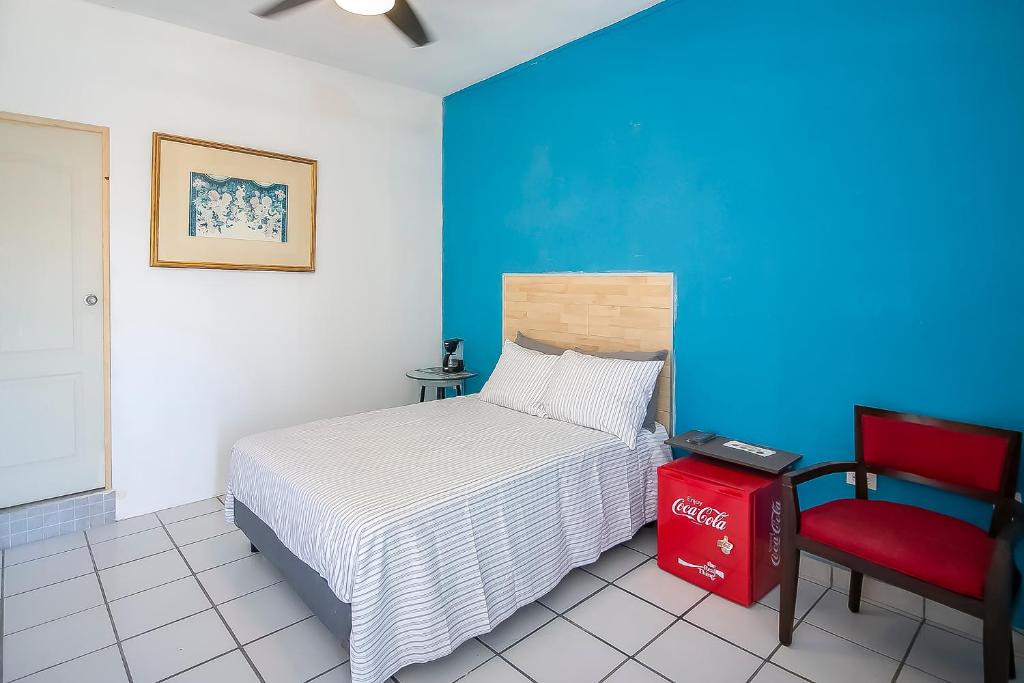 - une chambre avec un lit et une chaise rouge dans l'établissement OYO Hotel Plaza Las Torres, Cabo San Lucas, à Cabo San Lucas