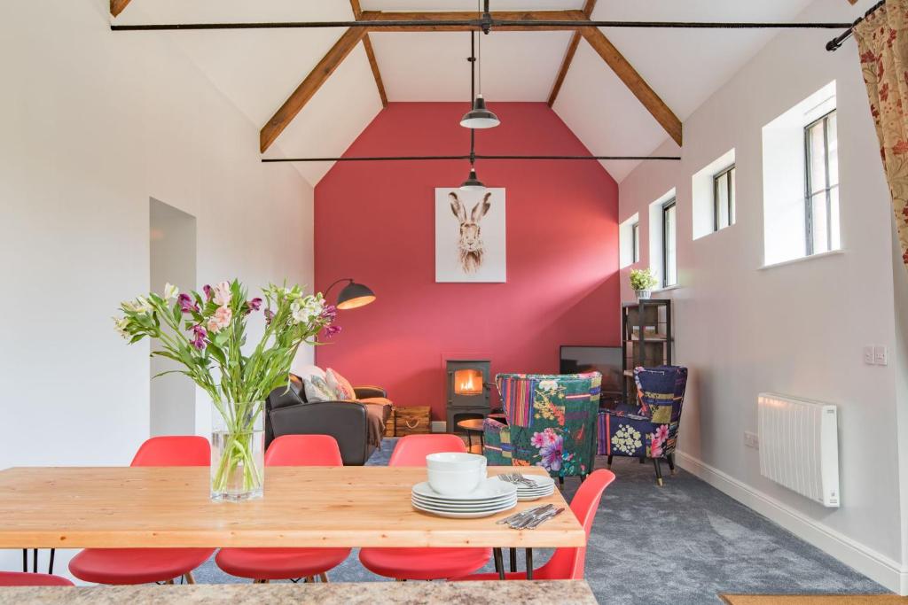 The Kennels by Bloom Stays في فيفرشام: غرفة طعام مع طاولة خشبية وجدران حمراء