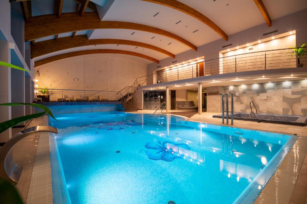 a large swimming pool with blue water in a building at Fala by Marena Wellness & Spa in Międzywodzie