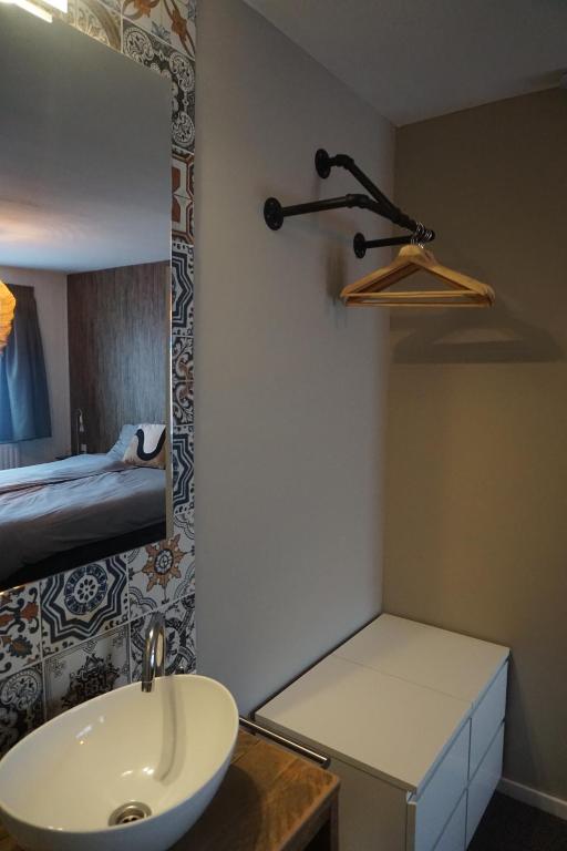 a bathroom with a sink and a mirror and a bed at Bed and Breakfast Kik en Bun in Katwijk aan Zee