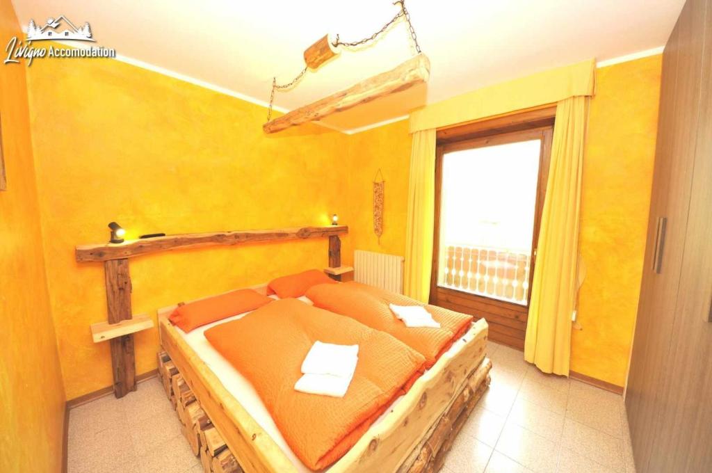 ein Schlafzimmer mit einem Bett in einem Zimmer mit einem Fenster in der Unterkunft Baita Carosello Apt 4 Adiacente Carosello 3000 in Livigno