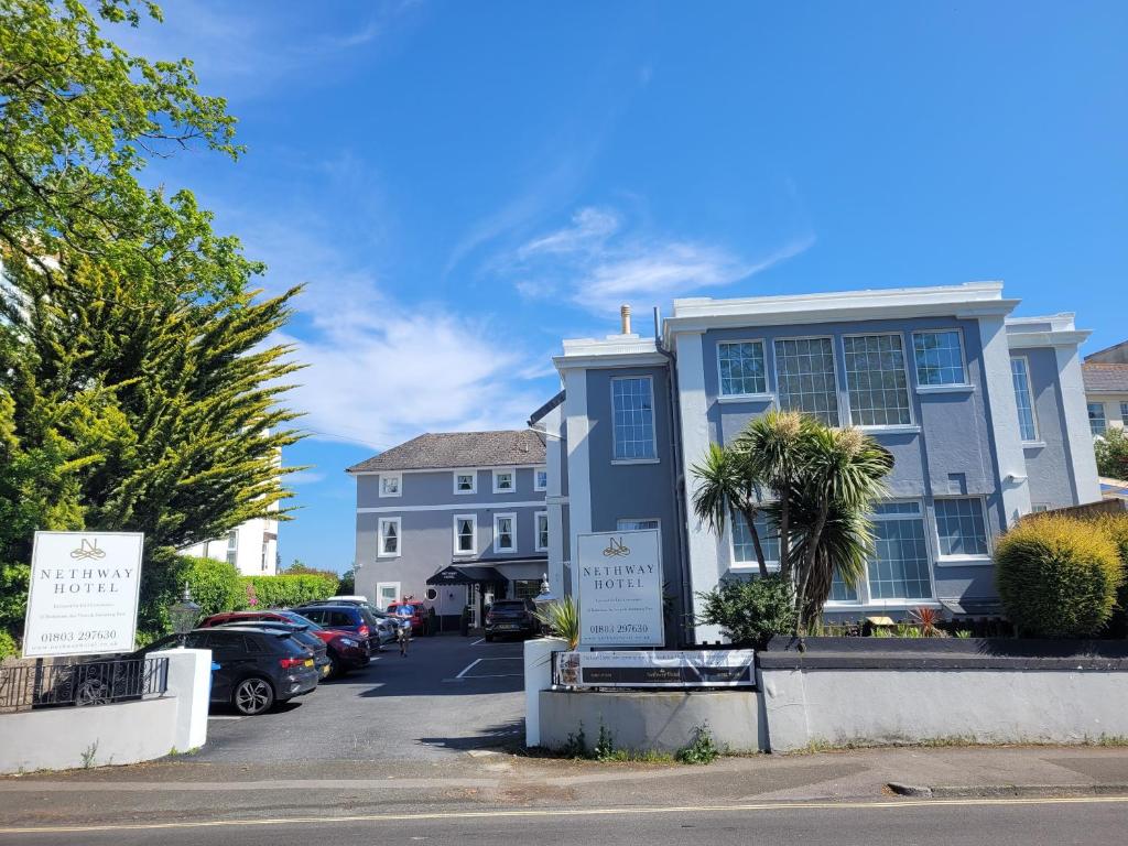 a blue house with cars parked in a parking lot at Nethway Hotel in Torquay