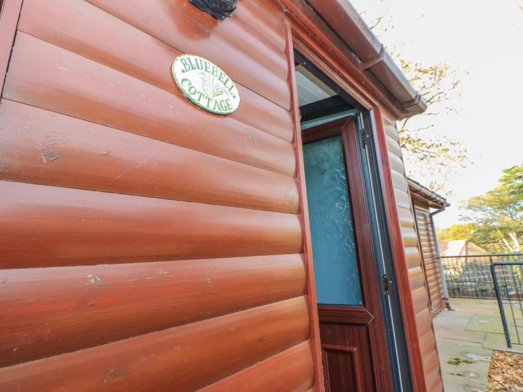 eine Holztür mit einem Schild an der Seite eines Hauses in der Unterkunft Bluebell Lodge in Saltburn-by-the-Sea