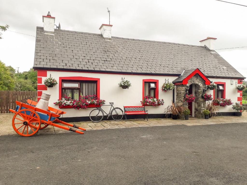 a red and white house with a red cart in front of it at Cookies Cottage in Ballyshannon