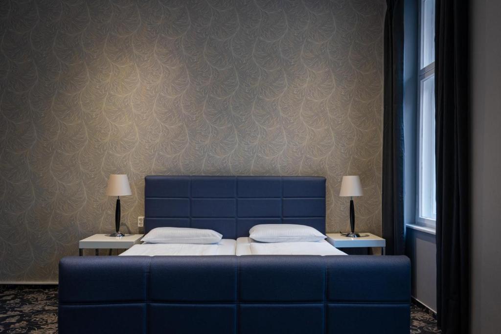 Hotel Gasteiner Hof في برلين: غرفة نوم بسرير ازرق وطاولتين مع لمبات