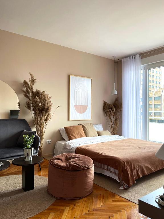 a bedroom with a large bed and a couch at Etern Stays IEG - Zen Apartment in Prishtinë