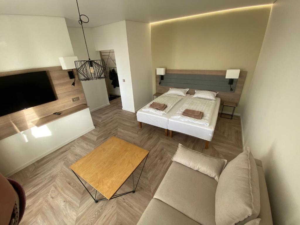 um pequeno quarto com uma cama e um sofá em MOYA Apartmentai em Naujoji Akmenė