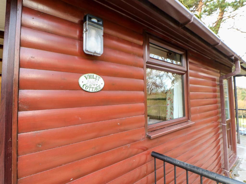 ソルトバーン・バイ・ザ・シーにあるViolet Lodgeの壁に看板が付いたログキャビン
