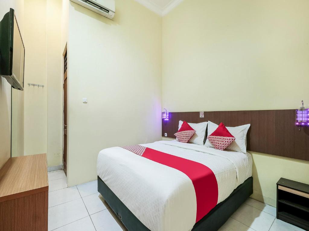 um quarto com uma cama grande com lençóis vermelhos e brancos em Super OYO 90910 Pondok Tamsis em Yogyakarta