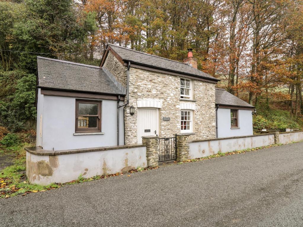 una pequeña casa de piedra al lado de una carretera en Penlon, en Aberystwyth