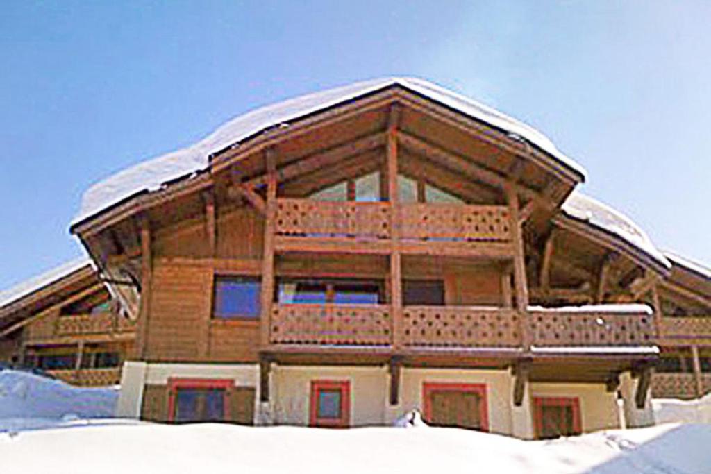 een groot houten gebouw met een met sneeuw bedekt dak bij superbe chalet Amitie jacuzzi proche lac et du centre avec reduction multipass ete in Les Gets