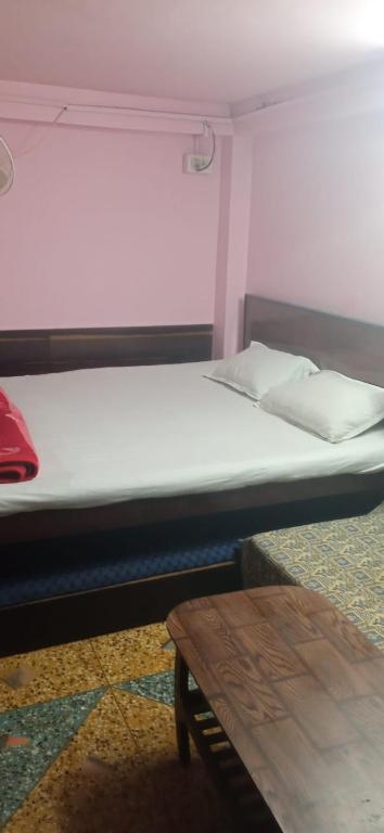 uma cama grande num quarto com uma mesa em Northeastern Dormitory em Gauripur