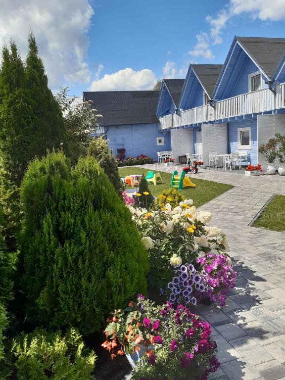 un jardin avec des fleurs et des buissons en face d'un bâtiment dans l'établissement Domki letniskowe U Tamary, à Grzybowo
