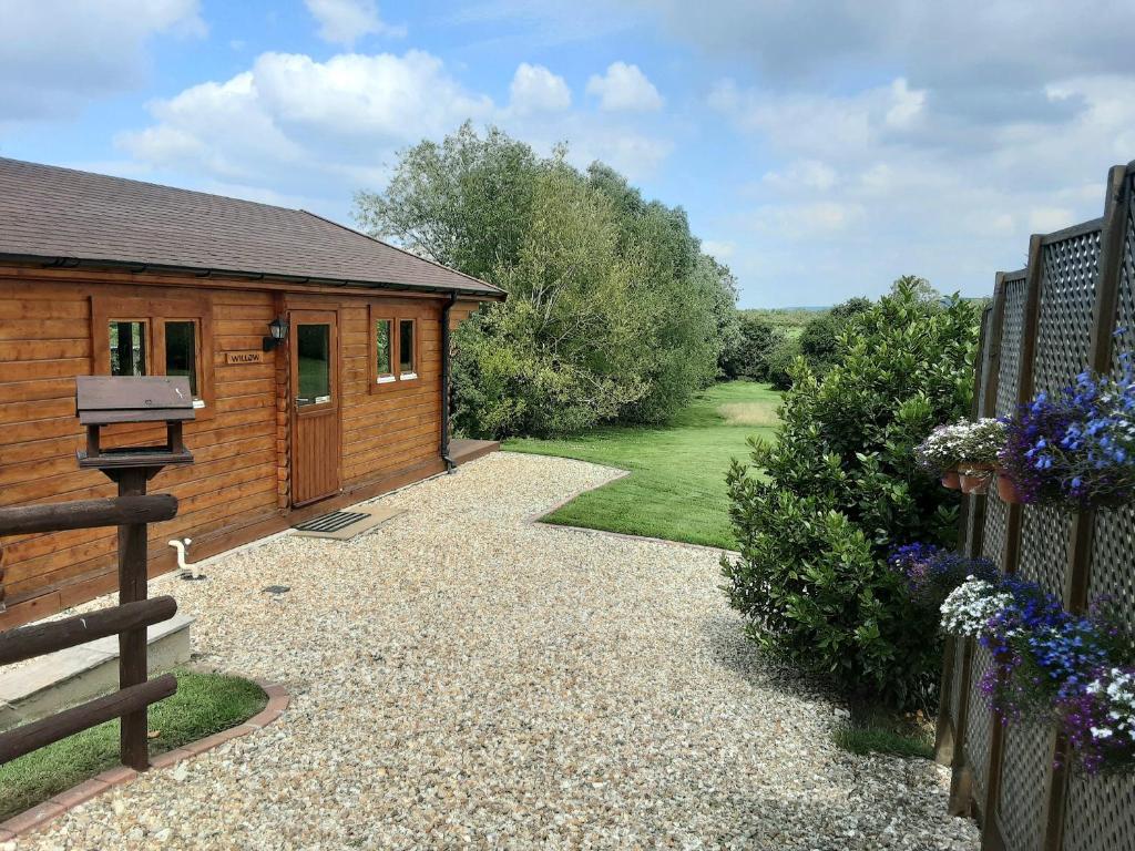 un patio trasero con una casa y una valla en Pennylands Willow Lodge, en Broadway