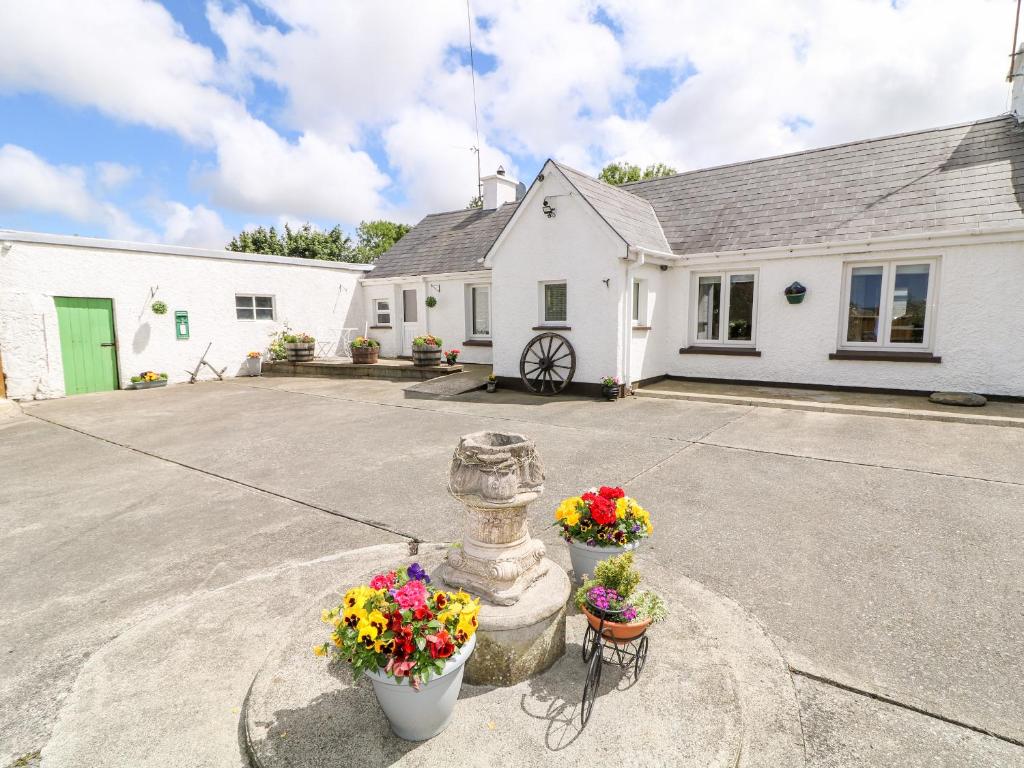 une maison blanche avec des fleurs devant elle dans l'établissement Whispering Willows - The Bungalow, à Craigtown