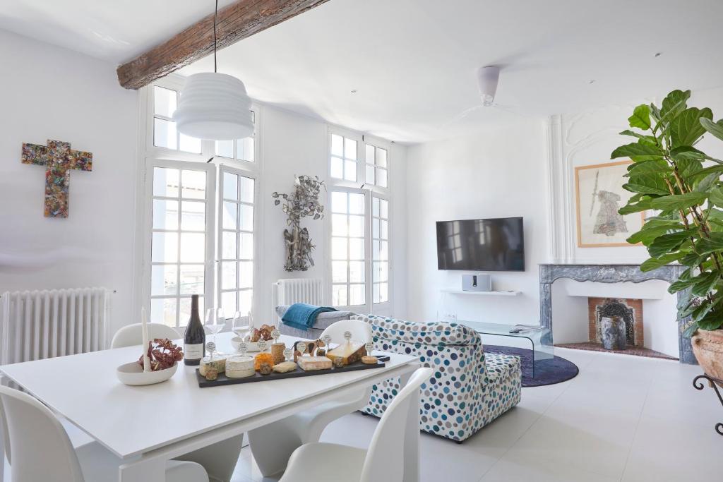 een witte woonkamer met een tafel en stoelen bij Beautiful Art Lovers Apartment in Béziers