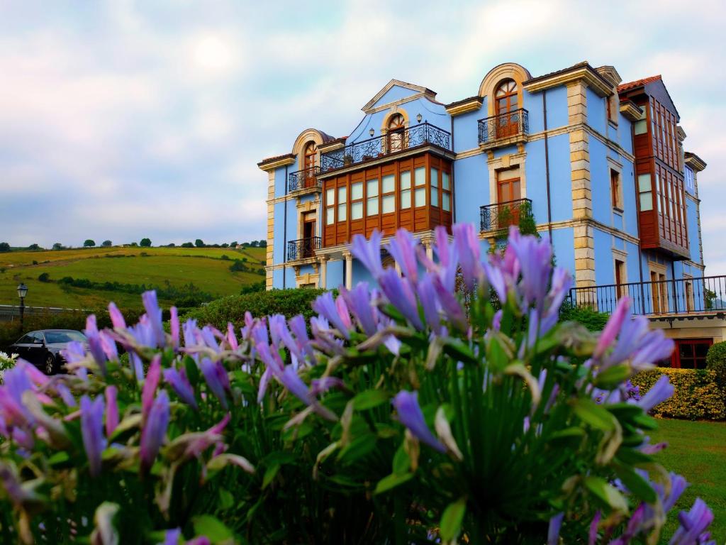 una casa con flores púrpuras delante de ella en Quinta de Villanueva, en Colombres