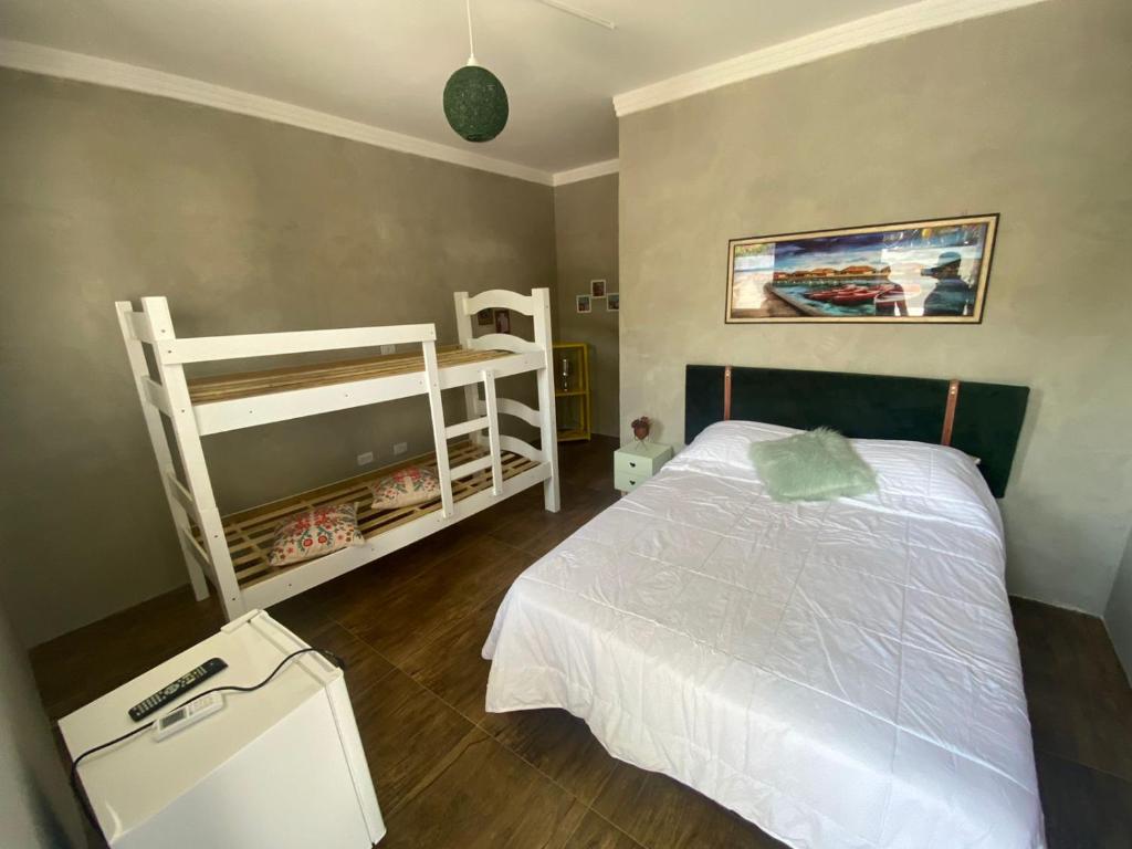 Suíte Luxo Refúgio das Ostras في غوارويا: غرفة نوم مع سرير وسريرين بطابقين
